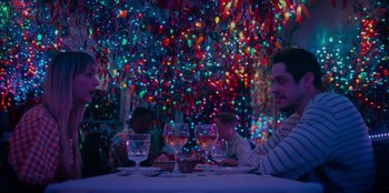 Movie still from “Meet Cute” (2022), directed by Alex Lehmann – A group of people sitting at a table with glasses of wine; Medium shot, Over the shoulder angle