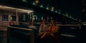 Movie still from “Meet Cute” (2022), directed by Alex Lehmann – A man and a woman sitting on a bench at night; Medium shot, High angle