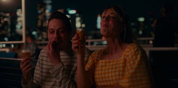 Movie still from “Meet Cute” (2022), directed by Alex Lehmann – A man and a woman sitting next to each other; Medium shot, Over the shoulder angle