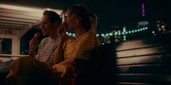 Movie still from “Meet Cute” (2022), directed by Alex Lehmann – A man and a woman sitting next to each other on a park bench; Medium shot, High angle