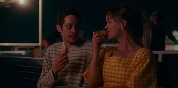 Movie still from “Meet Cute” (2022), directed by Alex Lehmann – A man and a woman are eating some food together; Medium shot, Over the shoulder angle
