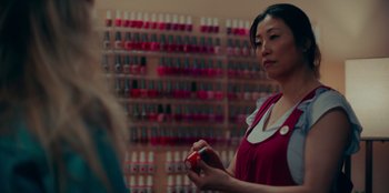 Movie still from “Meet Cute” (2022), directed by Alex Lehmann – A woman in a store holding a bottle of nail varnish; Close Up shot, High angle