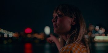 Movie still from “Meet Cute” (2022), directed by Alex Lehmann – A woman in a yellow and white checkered shirt looking up at the sky; Close Up shot, Low angle