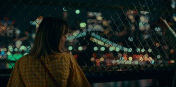Movie still from “Meet Cute” (2022), directed by Alex Lehmann – A woman looking out over a city at night; Medium shot, Over the shoulder angle