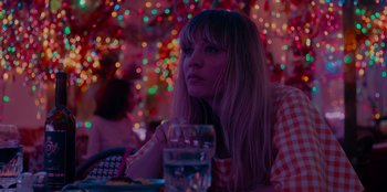 Movie still from “Meet Cute” (2022), directed by Alex Lehmann – A woman sitting at a table with a drink in front of her; Close Up shot, Low angle