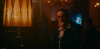 Movie still from “Meet Cute” (2022), directed by Alex Lehmann – A man is smoking a cigarette in a dark room; Medium shot, Low angle