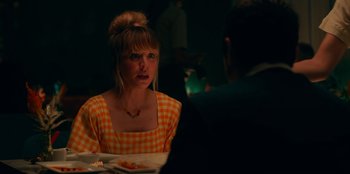 Movie still from “Meet Cute” (2022), directed by Alex Lehmann – A woman sitting at a dinner table with a man; Medium shot, Over the shoulder angle