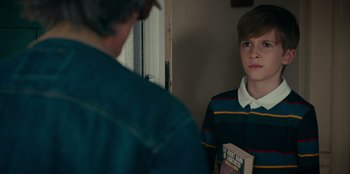 Movie still from “Meet Cute” (2022), directed by Alex Lehmann – Two boys are looking at each other in a room; Medium shot, Over the shoulder angle
