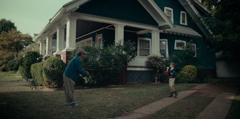 Movie still from “Meet Cute” (2022), directed by Alex Lehmann – A man and a boy are playing frisbee outside a house; Wide shot, Over the shoulder angle