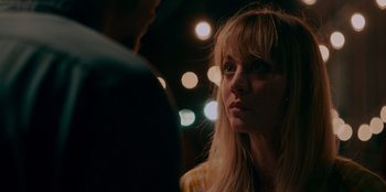 Movie still from “Meet Cute” (2022), directed by Alex Lehmann – A woman with blonde hair and a yellow shirt is looking at a man with blonde hair; Close Up shot, Over the shoulder angle