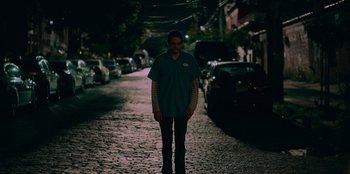 Movie still from “Meet Cute” (2022), directed by Alex Lehmann – A man standing on the side of a road at night; Wide shot, Low angle