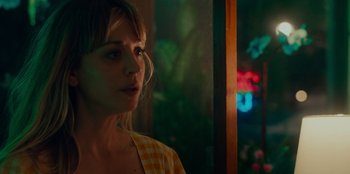 Movie still from “Meet Cute” (2022), directed by Alex Lehmann – A woman standing in front of a window with lights; Close Up shot, Over the shoulder angle