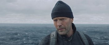 Movie still from “Meg 2: The Trench” (2023), directed by Ben Wheatley – A person wearing a jacket and a hat; Close Up shot, Low angle