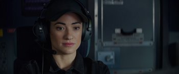 Movie still from “Meg 2: The Trench” (2023), directed by Ben Wheatley – A woman wearing a black hat and headphones; Close Up shot, Over the shoulder angle