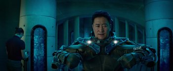 Movie still from “Meg 2: The Trench” (2023), directed by Ben Wheatley – A man in a suit with lights around his neck; Medium shot, Low angle