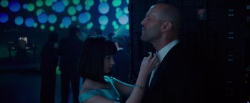 Movie still from “Meg 2: The Trench” (2023), directed by Ben Wheatley – A woman adjusting a man's neck tie in a dark room; Medium shot, Low angle