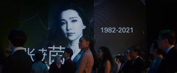 Movie still from “Meg 2: The Trench” (2023), directed by Ben Wheatley – A group of people standing in front of a wall with an image of a woman; Close Up shot, Over the shoulder angle