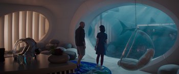 Movie still from “Meg 2: The Trench” (2023), directed by Ben Wheatley – A man and a woman standing in front of an aquarium; Wide shot, High angle