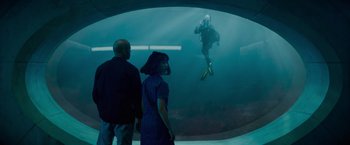 Movie still from “Meg 2: The Trench” (2023), directed by Ben Wheatley – Two people watching a scuba diver in the water; Wide shot, Over the shoulder angle