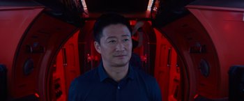 Movie still from “Meg 2: The Trench” (2023), directed by Ben Wheatley – A man standing in front of a red light; Close Up shot, Over the shoulder angle