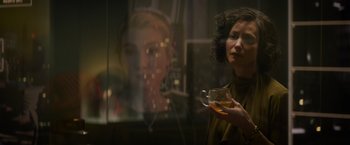 Movie still from “Meg 2: The Trench” (2023), directed by Ben Wheatley – A woman is holding a glass of tea in front of a mirror; Close Up shot, Over the shoulder angle