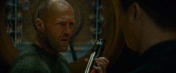 Movie still from “Meg 2: The Trench” (2023), directed by Ben Wheatley – A bald man holding a gun in his hand; Close Up shot, Low angle