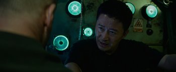 Movie still from “Meg 2: The Trench” (2023), directed by Ben Wheatley – A man standing in front of a group of green lights; Close Up shot, Over the shoulder angle