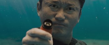Movie still from “Meg 2: The Trench” (2023), directed by Ben Wheatley – A man holding an object up to his face; Extreme Close Up shot, High angle