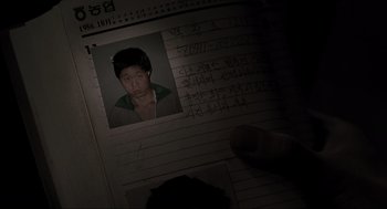Movie still from “Memories of Murder” (2003), directed by Bong Joon Ho – A picture of an asian man is on top of a notebook; Extreme Close Up shot, Overhead angle