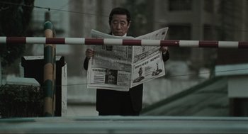 Movie still from “Memories of Murder” (2003), directed by Bong Joon Ho – A man is reading a newspaper on the side of the road; Close Up shot, Low angle