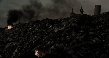 Movie still from “Memories of Murder” (2003), directed by Bong Joon Ho – A man standing on top of a pile of garbage; Extreme Wide shot, Low angle
