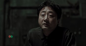 Movie still from “Memories of Murder” (2003), directed by Bong Joon Ho – A person sitting down with his eyes wide open; Close Up shot, Low angle