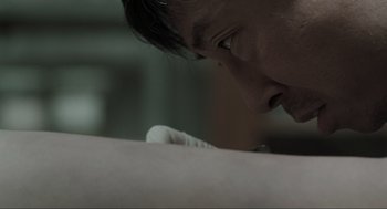 Movie still from “Memories of Murder” (2003), directed by Bong Joon Ho – A man's face as he leans over a bed; Extreme Close Up shot, Over the shoulder angle