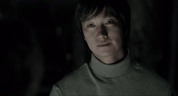 Movie still from “Memories of Murder” (2003), directed by Bong Joon Ho – A man with short black hair wearing a gray shirt; Close Up shot, Low angle