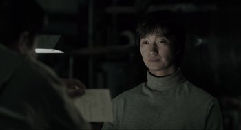 Movie still from “Memories of Murder” (2003), directed by Bong Joon Ho – A man holding a piece of paper while standing in a dark room; Close Up shot, Over the shoulder angle