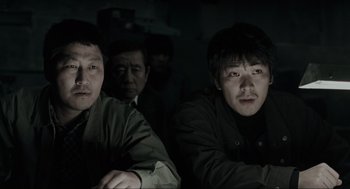 Movie still from “Memories of Murder” (2003), directed by Bong Joon Ho – A group of men sitting next to each other in the dark; Close Up shot, Low angle