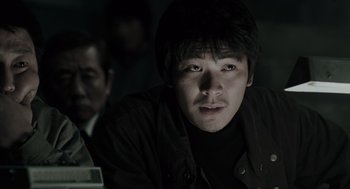 Movie still from “Memories of Murder” (2003), directed by Bong Joon Ho – A man sitting in front of another man in a dark room; Close Up shot, Low angle