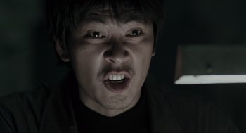 Movie still from “Memories of Murder” (2003), directed by Bong Joon Ho – A person's face in a dark room; Close Up shot, Low angle