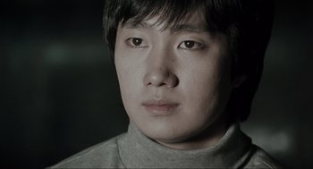 Movie still from “Memories of Murder” (2003), directed by Bong Joon Ho – A person wearing a gray shirt; Close Up shot, Low angle