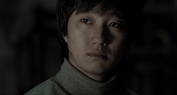 Movie still from “Memories of Murder” (2003), directed by Bong Joon Ho – A person wearing a gray sweater; Close Up shot, Low angle