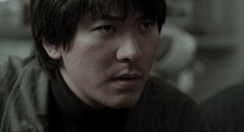 Movie still from “Memories of Murder” (2003), directed by Bong Joon Ho – A person wearing a black shirt; Close Up shot, Low angle