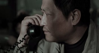 Movie still from “Memories of Murder” (2003), directed by Bong Joon Ho – A person talking on a phone; Close Up shot, High angle
