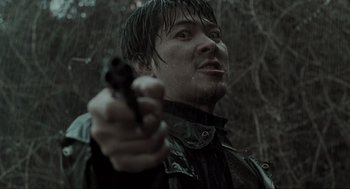 Movie still from “Memories of Murder” (2003), directed by Bong Joon Ho – A man holding a gun while standing in the rain; Close Up shot, Low angle