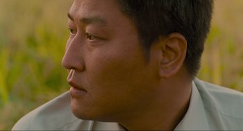 Movie still from “Memories of Murder” (2003), directed by Bong Joon Ho – A man's face in a field; Close Up shot, Over the shoulder angle