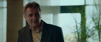 Movie still from “Memory” (2022), directed by Martin Campbell – A person wearing a suit and tie; Close Up shot, Over the shoulder angle