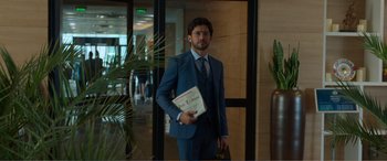 Movie still from “Memory” (2022), directed by Martin Campbell – A man in a suit and tie holding a book; Medium shot, Over the shoulder angle