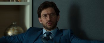 Movie still from “Memory” (2022), directed by Martin Campbell – A person wearing a suit and tie; Close Up shot, Over the shoulder angle