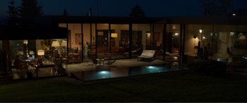 Movie still from “Memory” (2022), directed by Martin Campbell – A woman standing in front of a pool at night; Extreme Wide shot, High angle