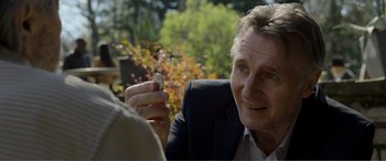 Movie still from “Memory” (2022), directed by Martin Campbell – An older man is holding a coin in his hand; Close Up shot, Over the shoulder angle