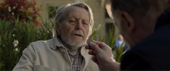 Movie still from “Memory” (2022), directed by Martin Campbell – An older man is being examined by an older person; Close Up shot, Over the shoulder angle